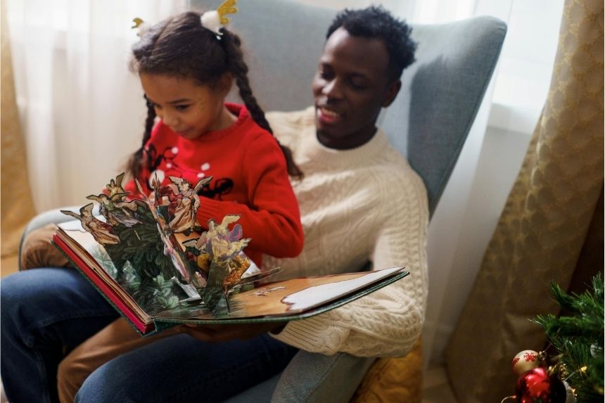 Dad and daughter reading a pop up book as a means to Making Christmas Memorable for Your Disabled or Neurodivergent Child