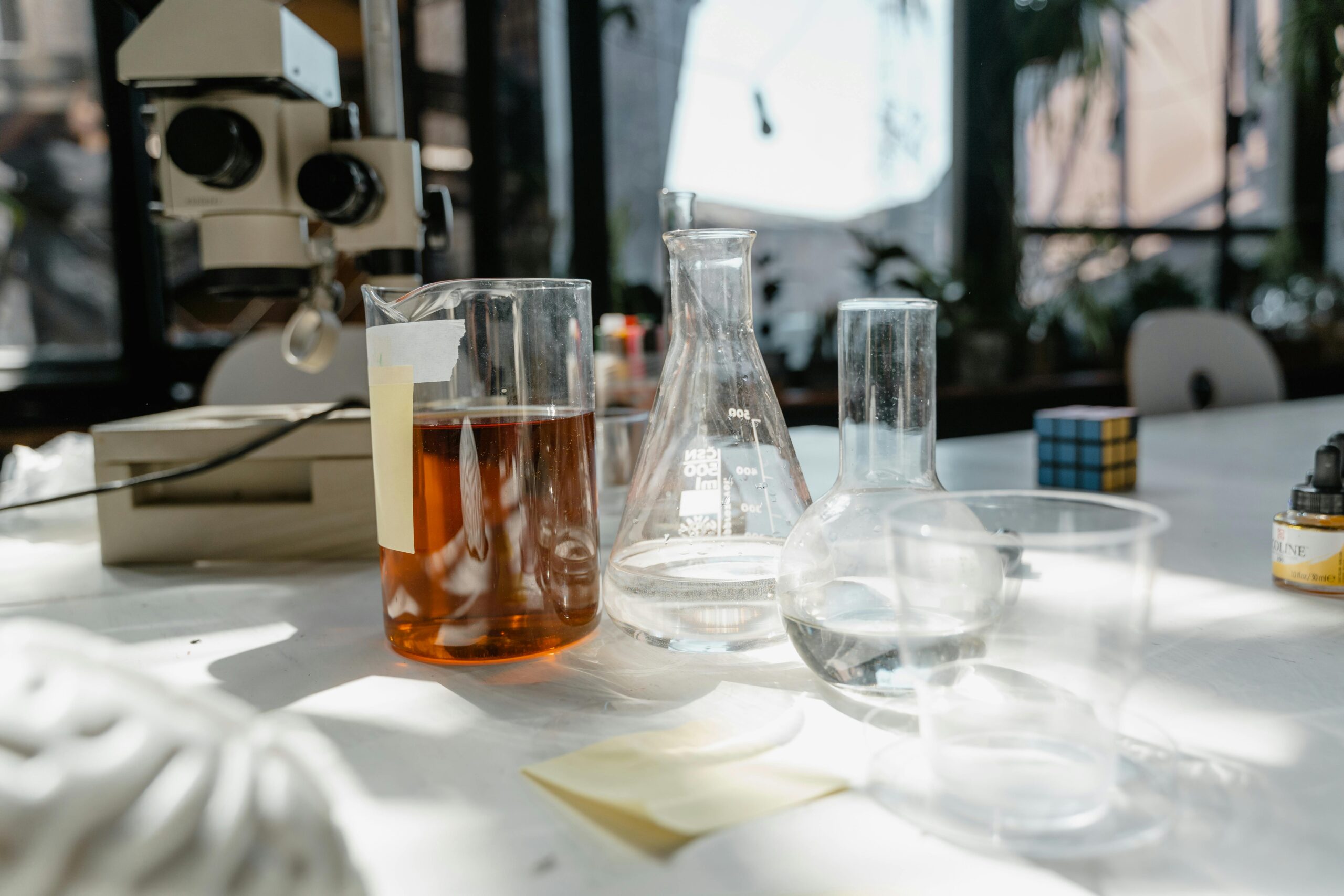 A set of chemistry tools including beakers and a microscope sit on a table