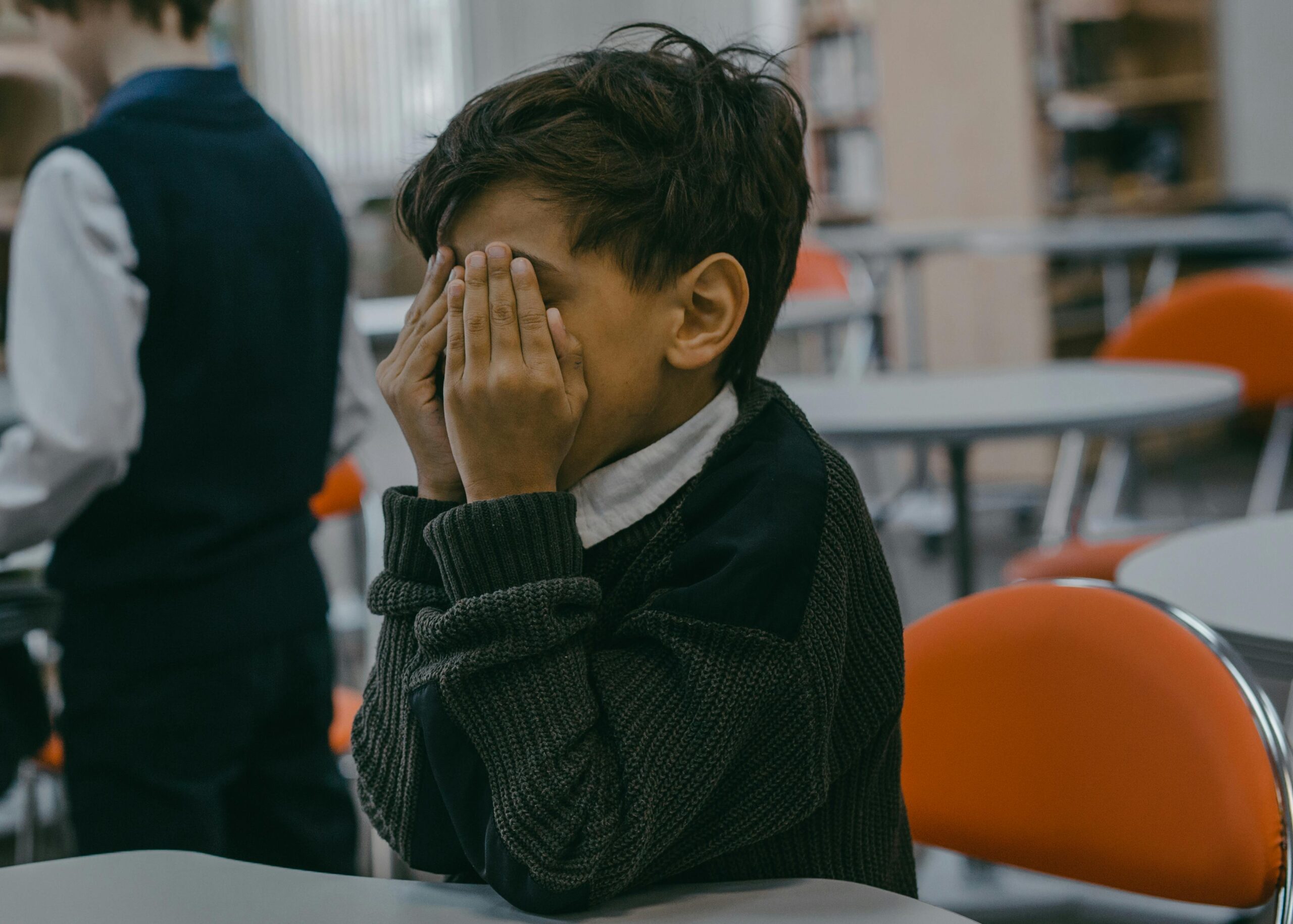 Distressed child holding hands to his face